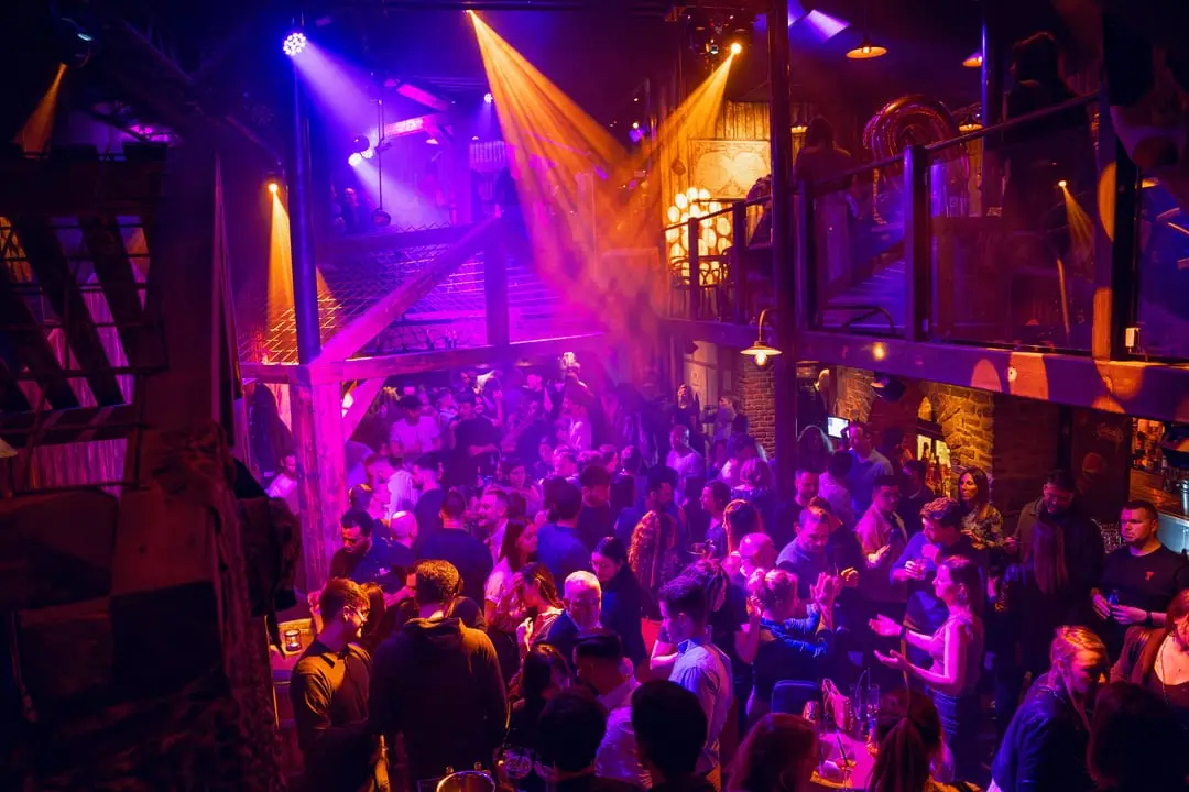 Soirée clubbing aux Granges : la piste bondée sous les jeux de lumière, vue depuis la mezzanine.