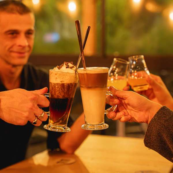Clients d'une brasserie qui trinquent avec leurs cafés et boissons alcoolisées. Brasserie Les Granges à Tilff.